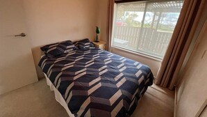Una camera da letto con un letto, un comodino, una finestra con tende e vista su un balcone.