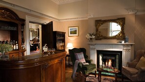 A traditional room with a bar area, a fireplace, and a green armchair. - Ardtara Country House (Maghera)
