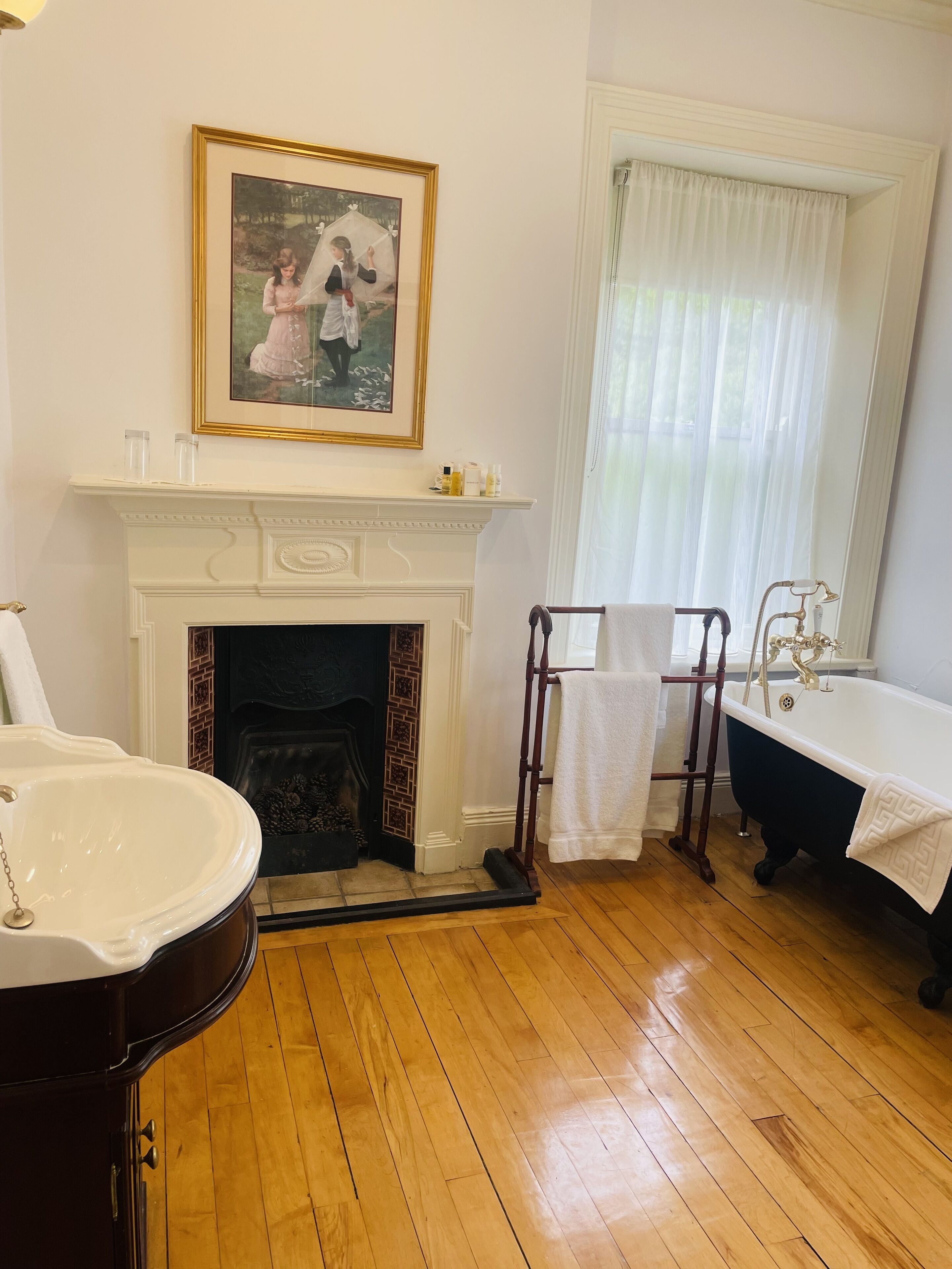 Un baño con chimenea blanca, una bañera independiente y un espejo grande.