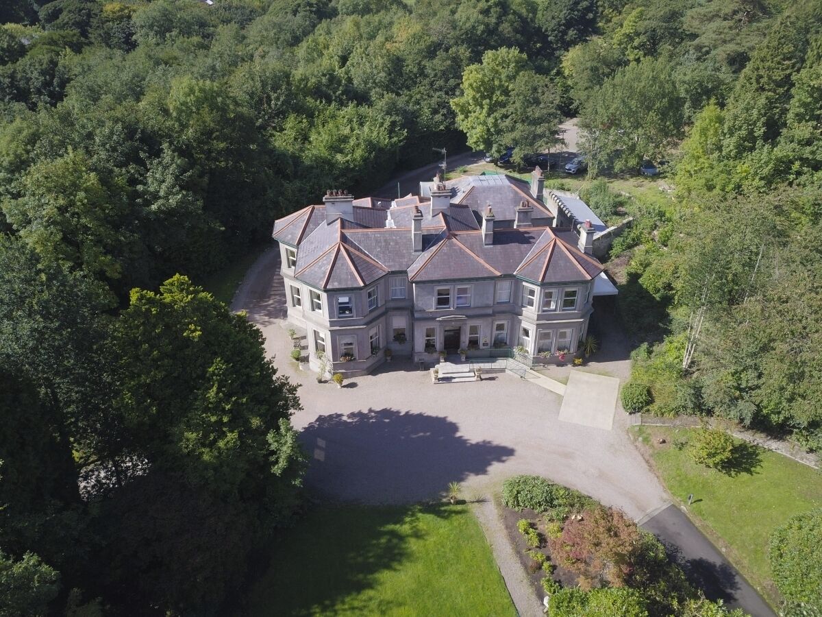 A large, multi-story building surrounded by lush greenery.