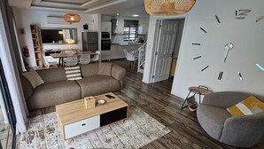 A modern living room with a sofa, coffee table, and a dining area with chairs and a table. - Villa with pool 5 minutes from the beach! (Trou-aux-Biches)