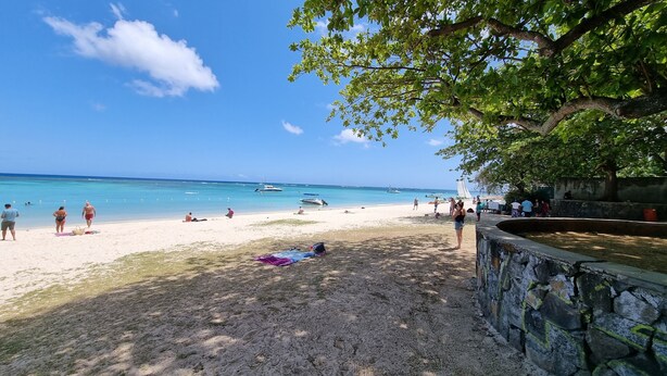 A beach with clear blue water, people relaxing, and boats in the distance. - Villa with pool 5 minutes from the beach! (Trou-aux-Biches)