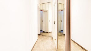 A hallway with a mirrored closet door, a tiled floor, and a plain white wall. - MASSENA AP4312 By Riviera Holiday Homes (Niza)