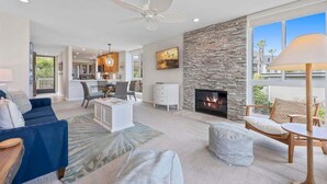 A spacious living room with a fireplace, a dining area, and a kitchen in the background. - G38 Harbor Cottage at North Coast Village - Beautiful Ocean Views *Super Close to Beach* (Oceanside)