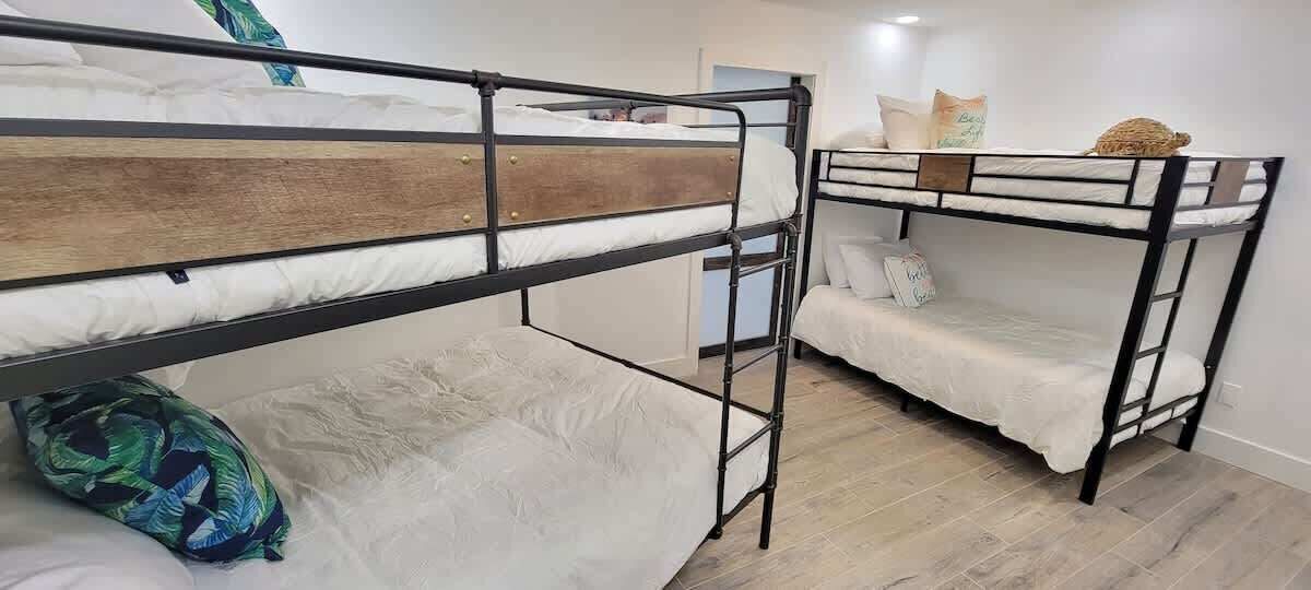 A room with two bunk beds, each with a wooden headboard and metal frame.