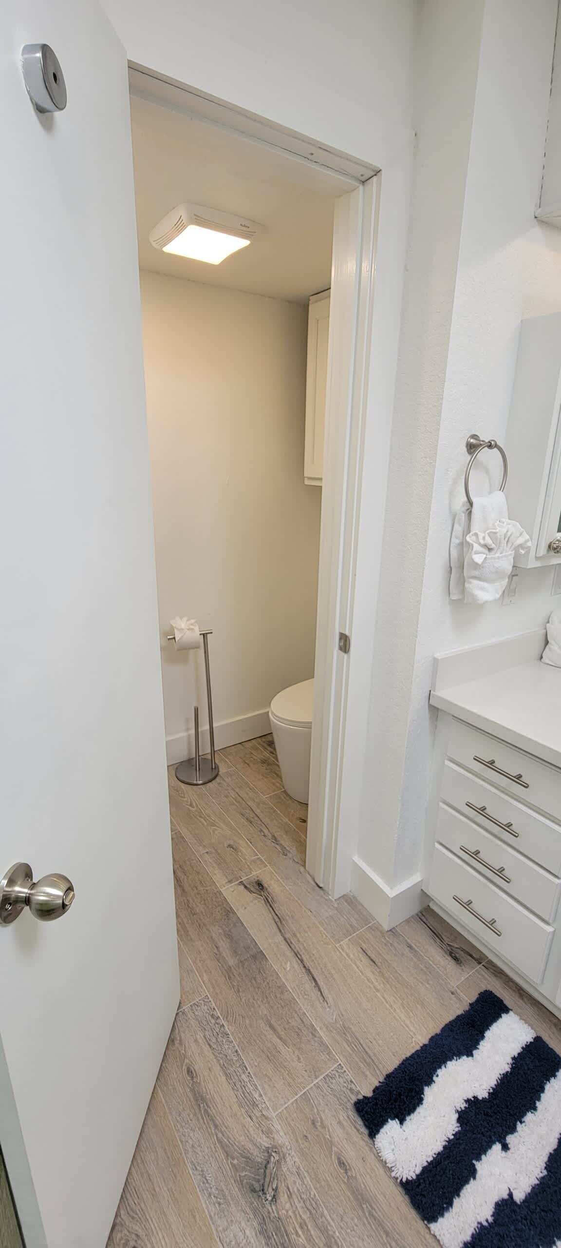 A bathroom with a toilet, a towel rack, a mirror, and a sink.