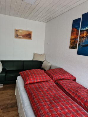 Una habitación con una cama, un sofá verde y dos cuadros en la pared.