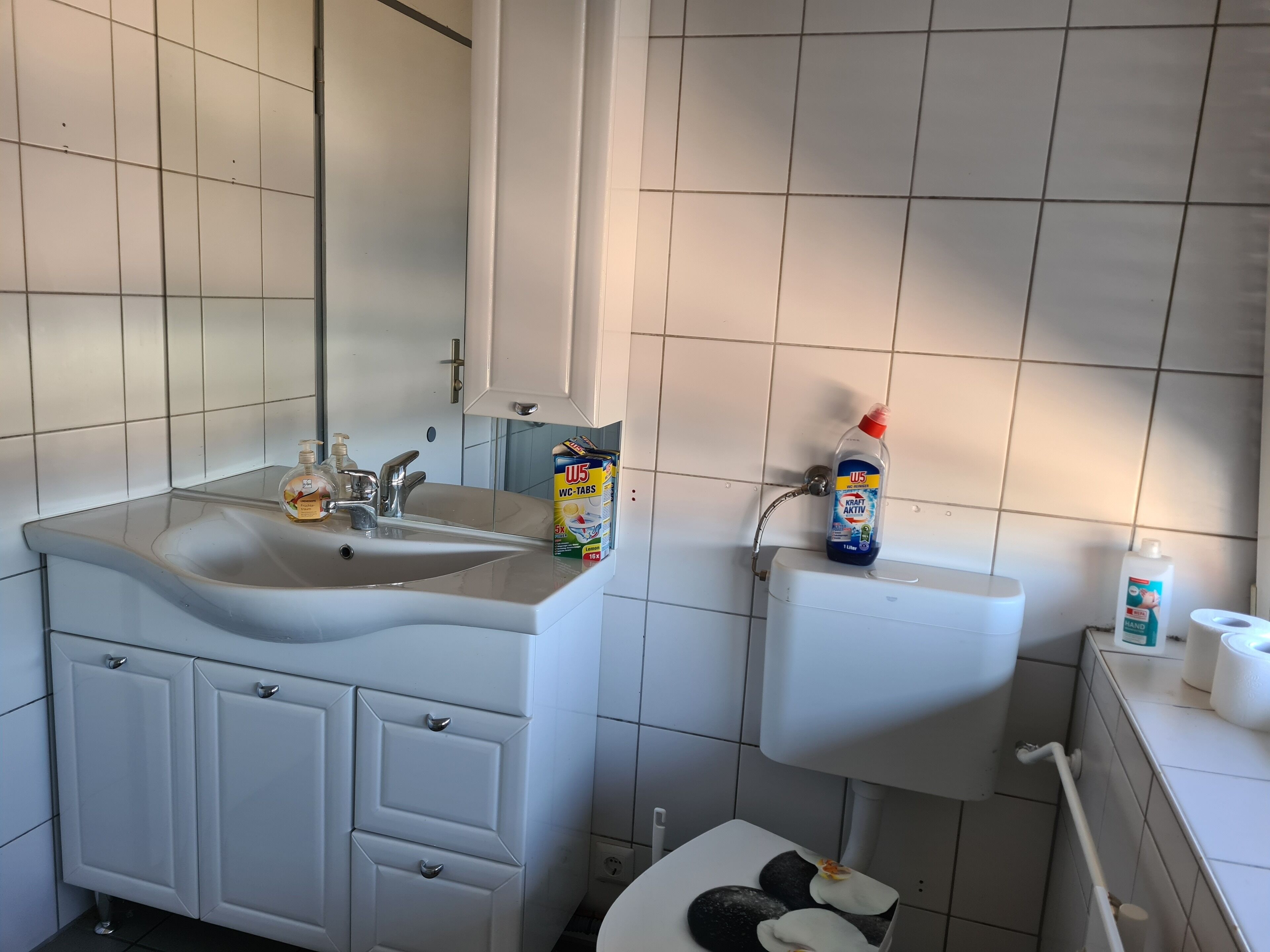 A bathroom with a sink, toilet, and storage cabinets.