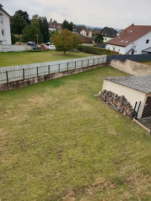 Zona residencial con patio cercado, un cobertizo pequeño y casas al fondo.