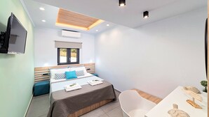 A modern bedroom with a bed, bedside table, and a small seating area. - Stavento Luxury Villa Private Pool (Chania)