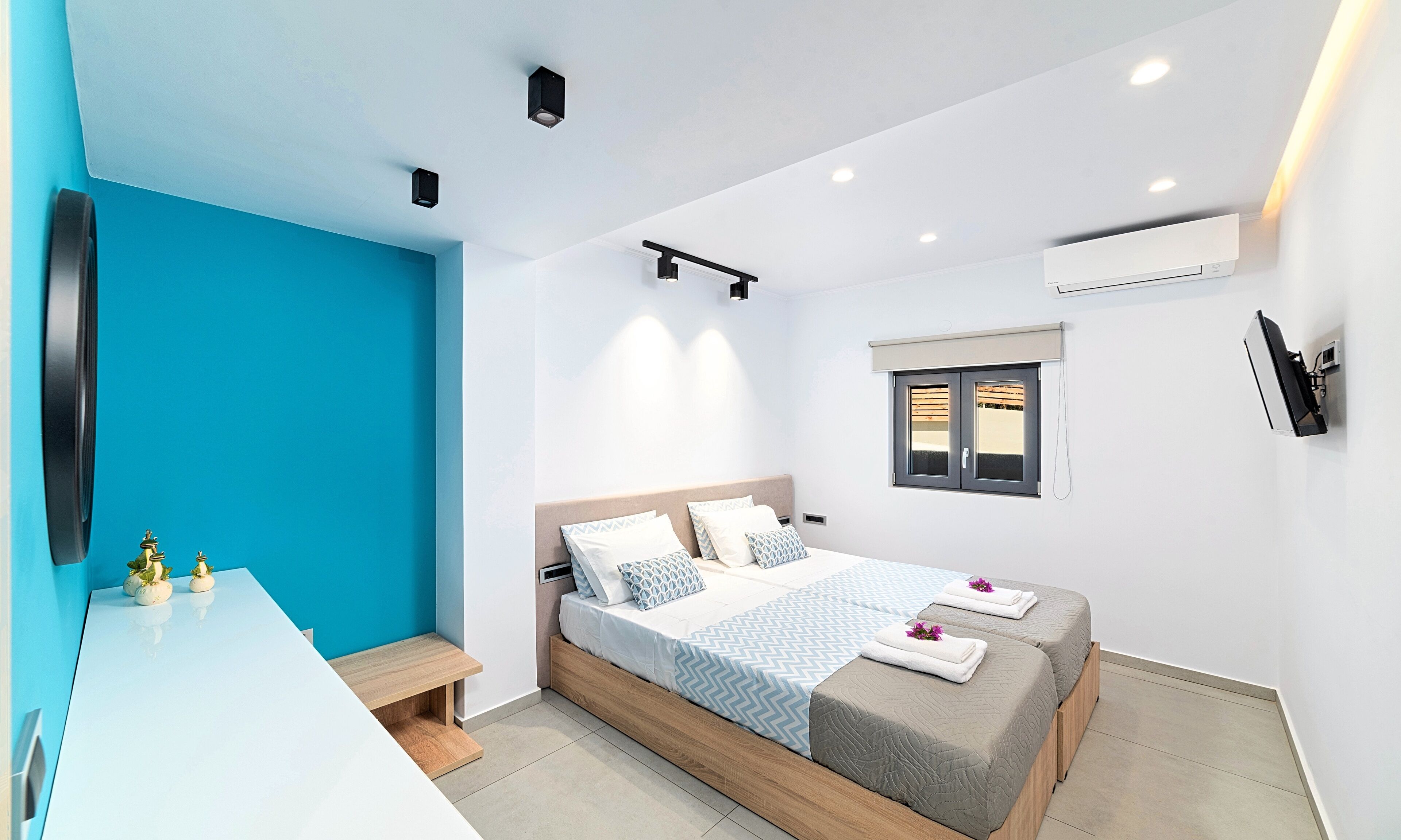 Een moderne slaapkamer met een bed, nachtkastjes, een raam en een airconditioning.