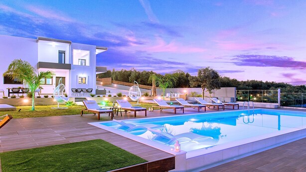A modern outdoor pool area with lounge chairs and a contemporary building in the background. - Stavento Luxury Villa Private Pool (Chania)