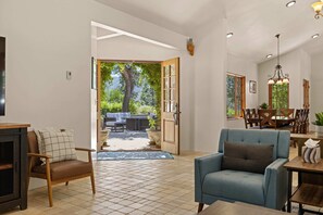 Ein geräumiges Wohnzimmer mit Esstisch, Stühlen und Blick ins Freie.