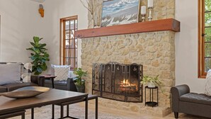 Una sala de estar con chimenea de piedra, un sofá, una mesa y una planta en maceta.