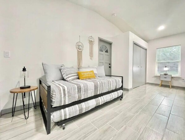 Une chambre à coucher moderne avec un lit, une table de chevet, une lampe et une fenêtre avec des stores.