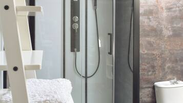 A modern bathroom with a glass-enclosed shower, a white toilet, and a wooden ladder.