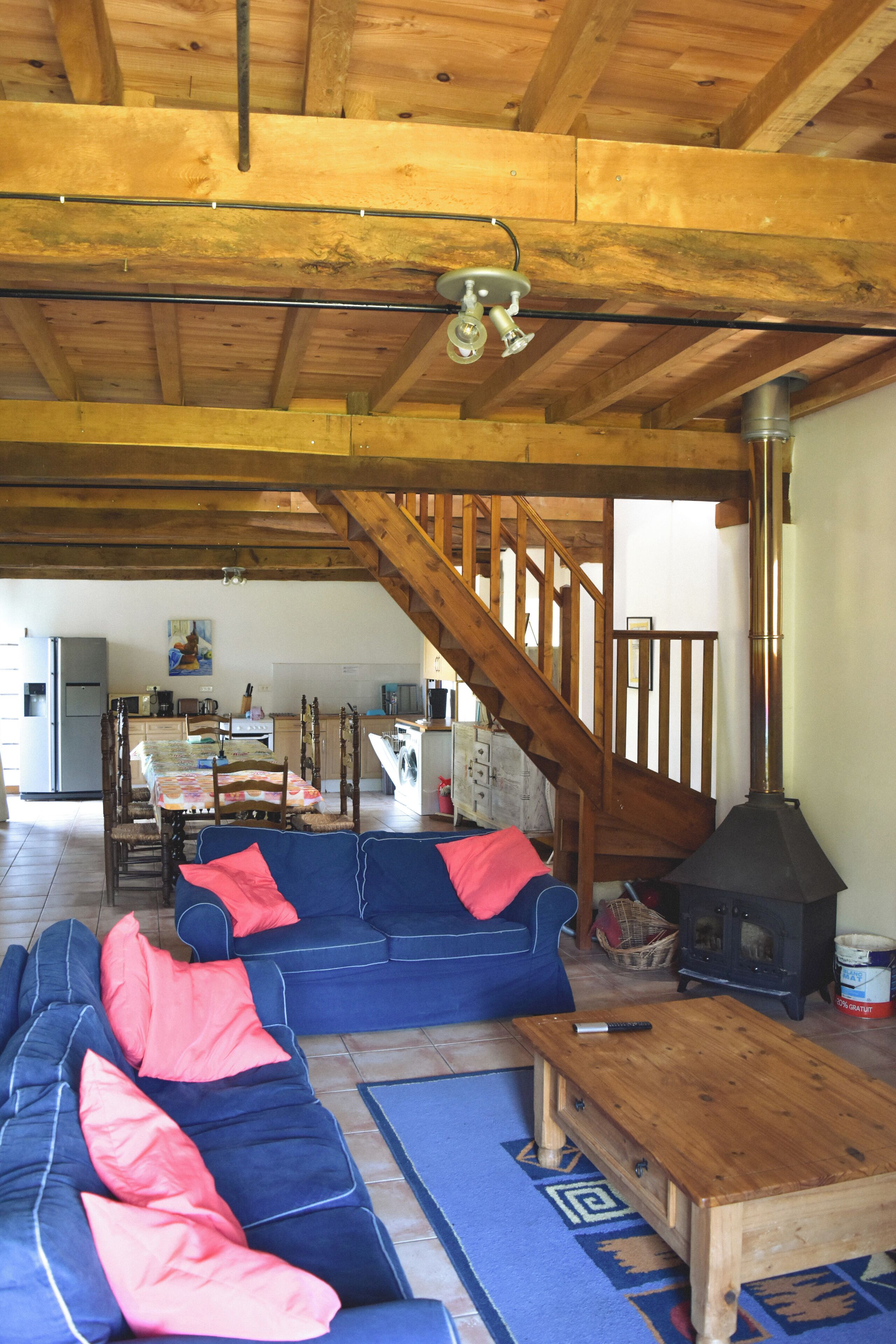 A cozy living room with a blue sofa, wooden coffee table, and a staircase leading to an upper level.