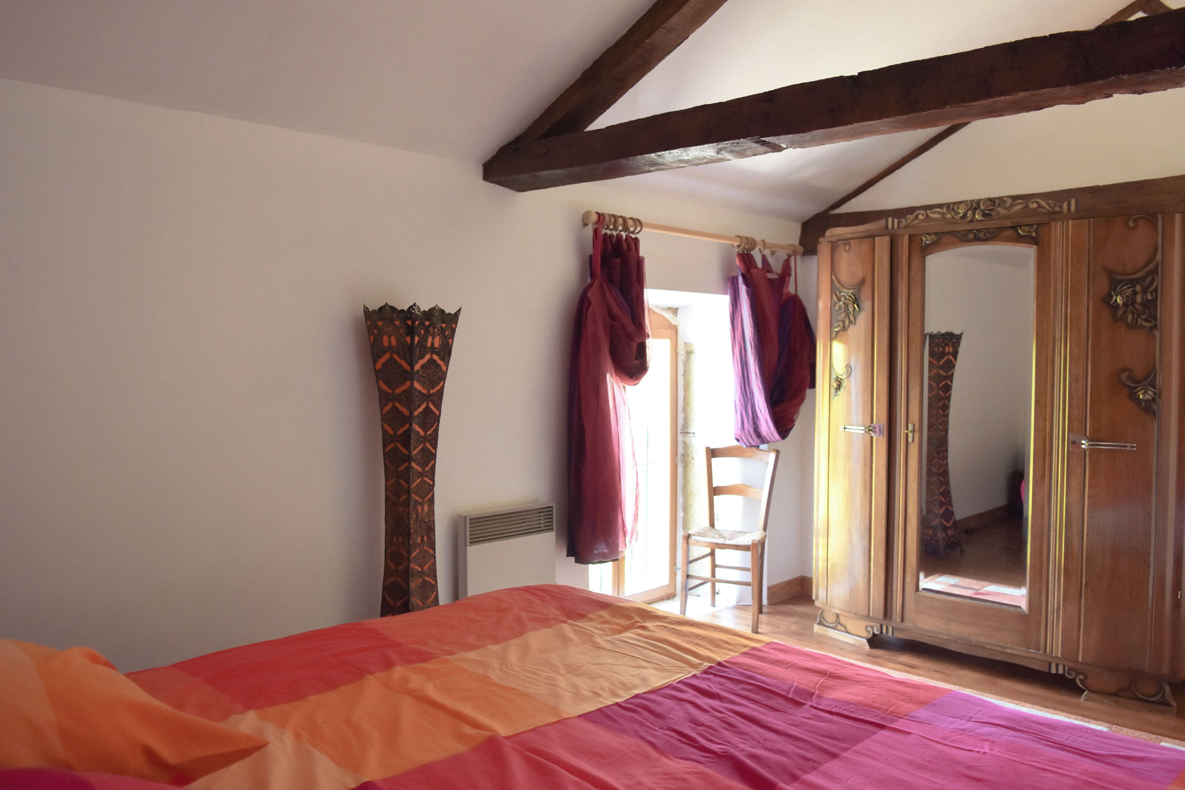 Un dormitorio con cama, armario y una silla.