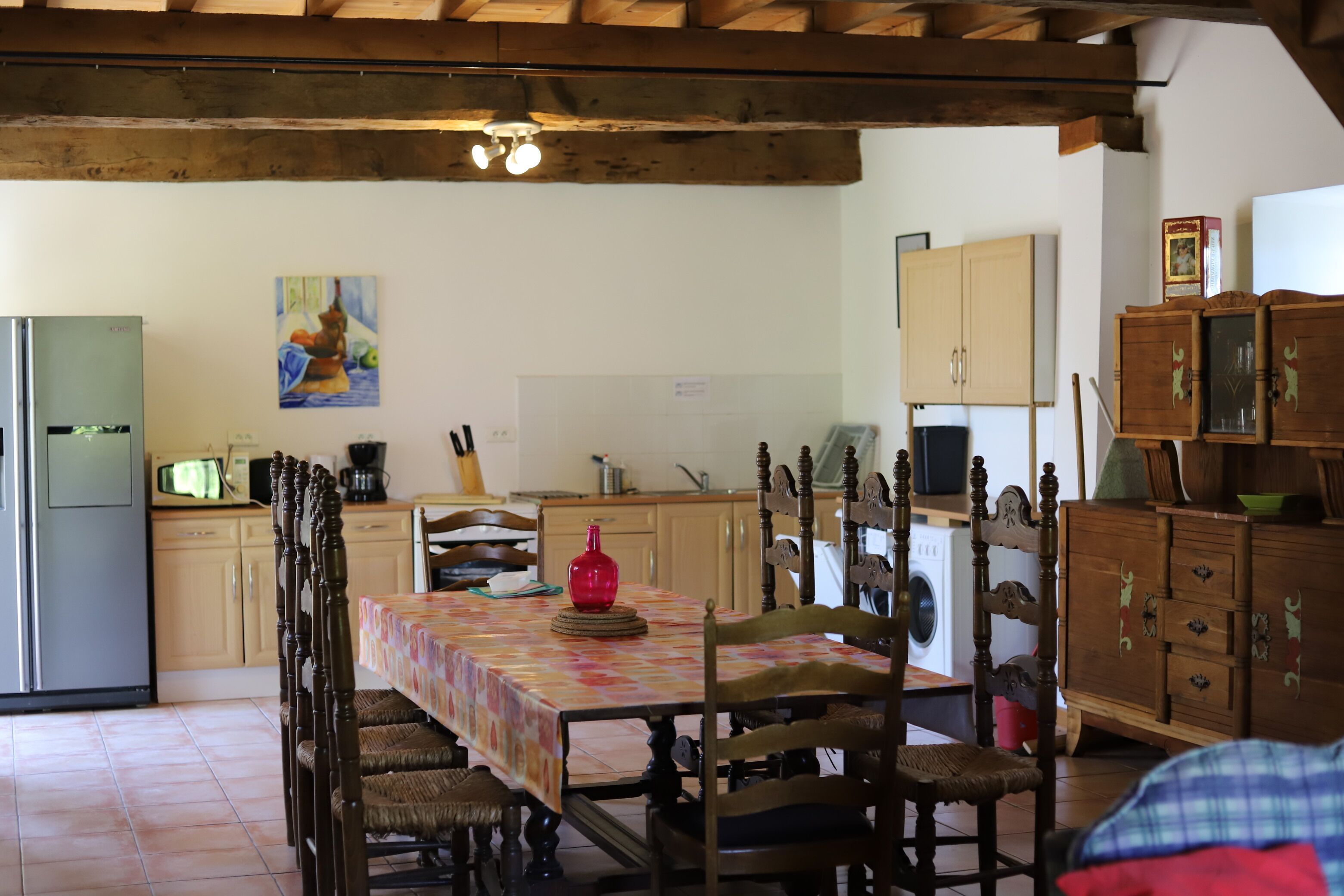 Una cocina con armarios de madera, una mesa de comedor con sillas y un refrigerador.