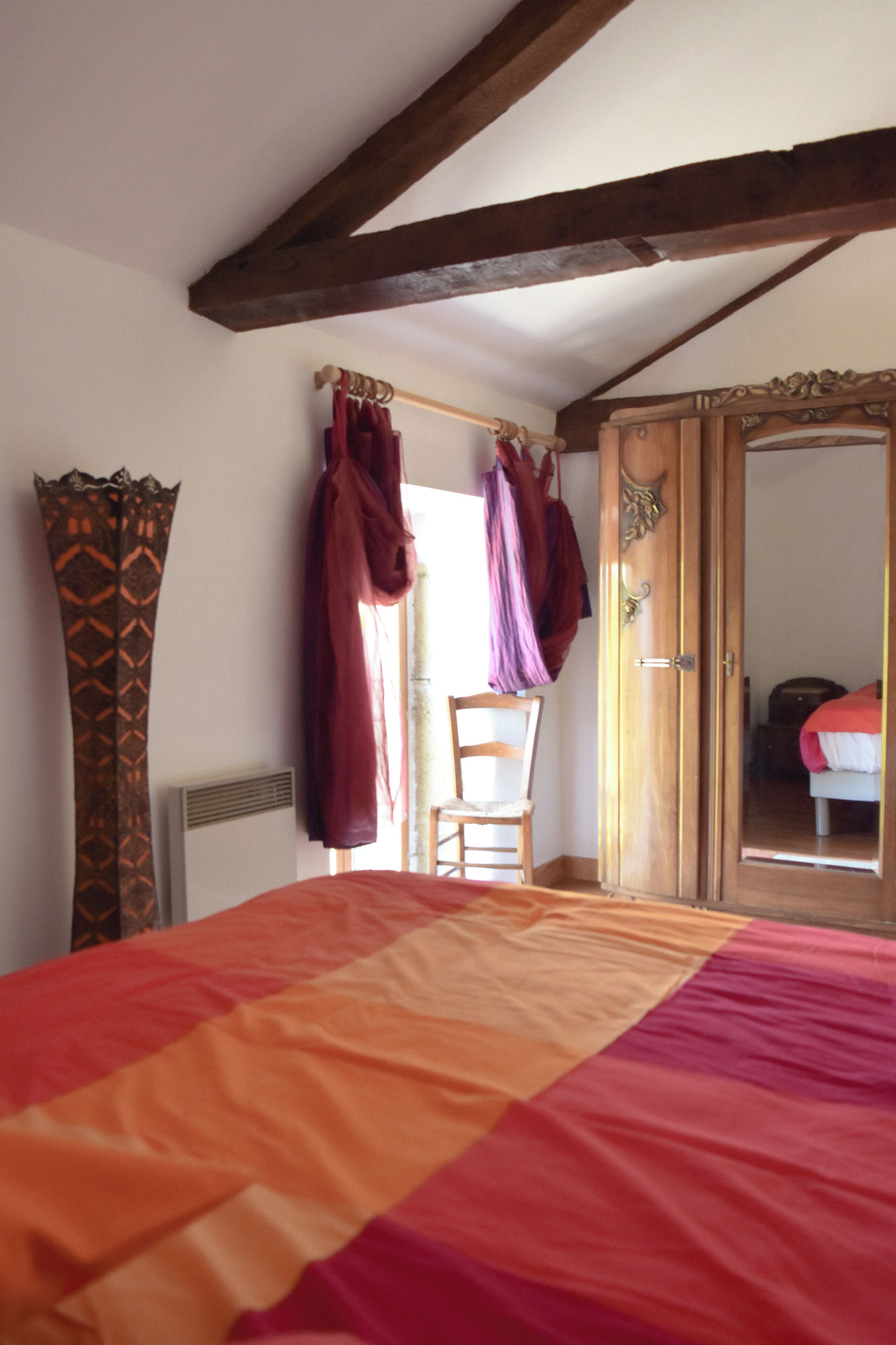 Een slaapkamer met een bed, een houten garderobe en een stoel.