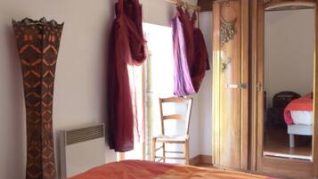 Een slaapkamer met een bed, een houten garderobe en een stoel.