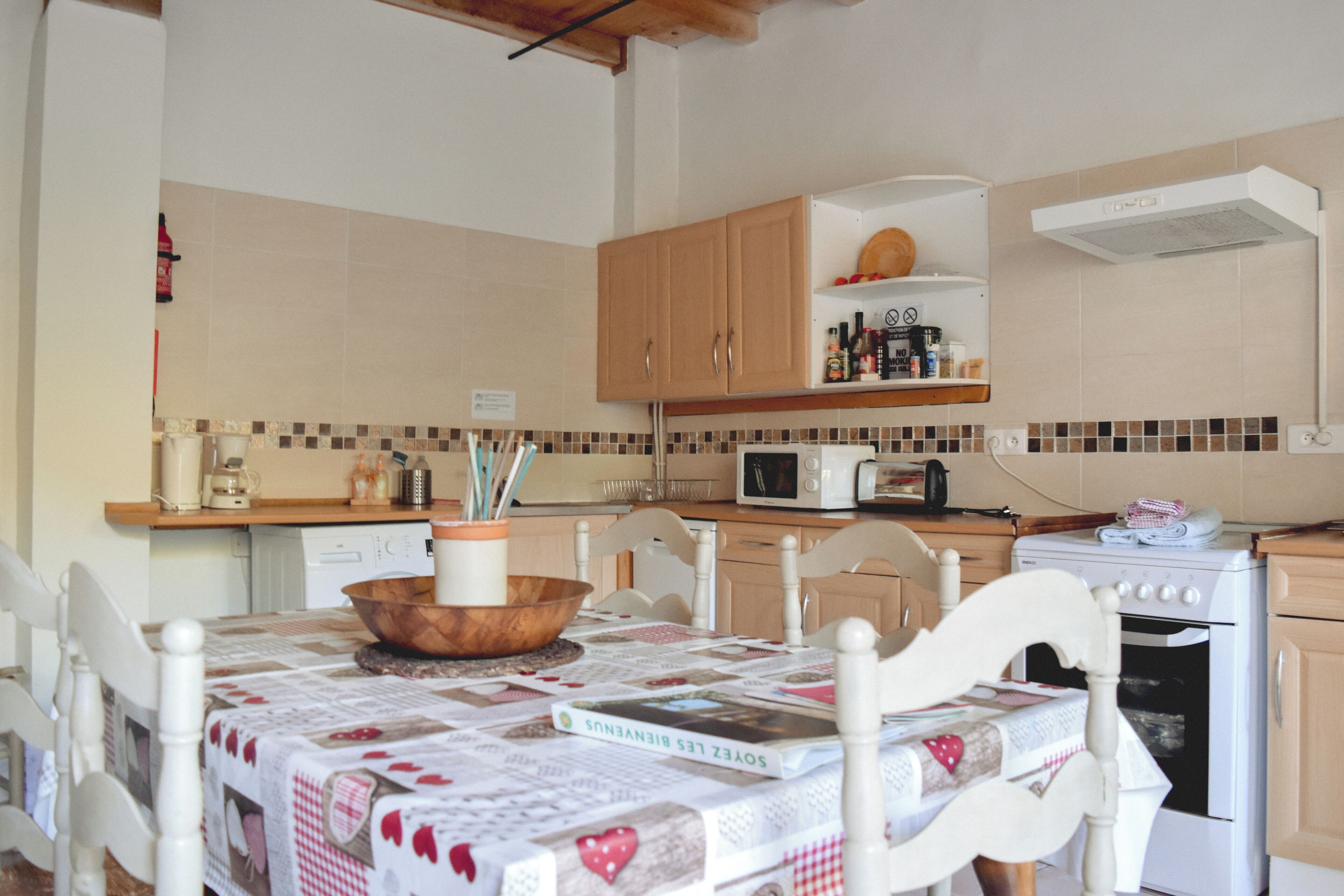 A kitchen with wooden cabinets, a microwave, a stove, and a table with a quilted tablecloth.