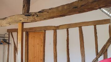 A bedroom with exposed wooden beams, a wooden door, and a bed with a colorful bedspread.