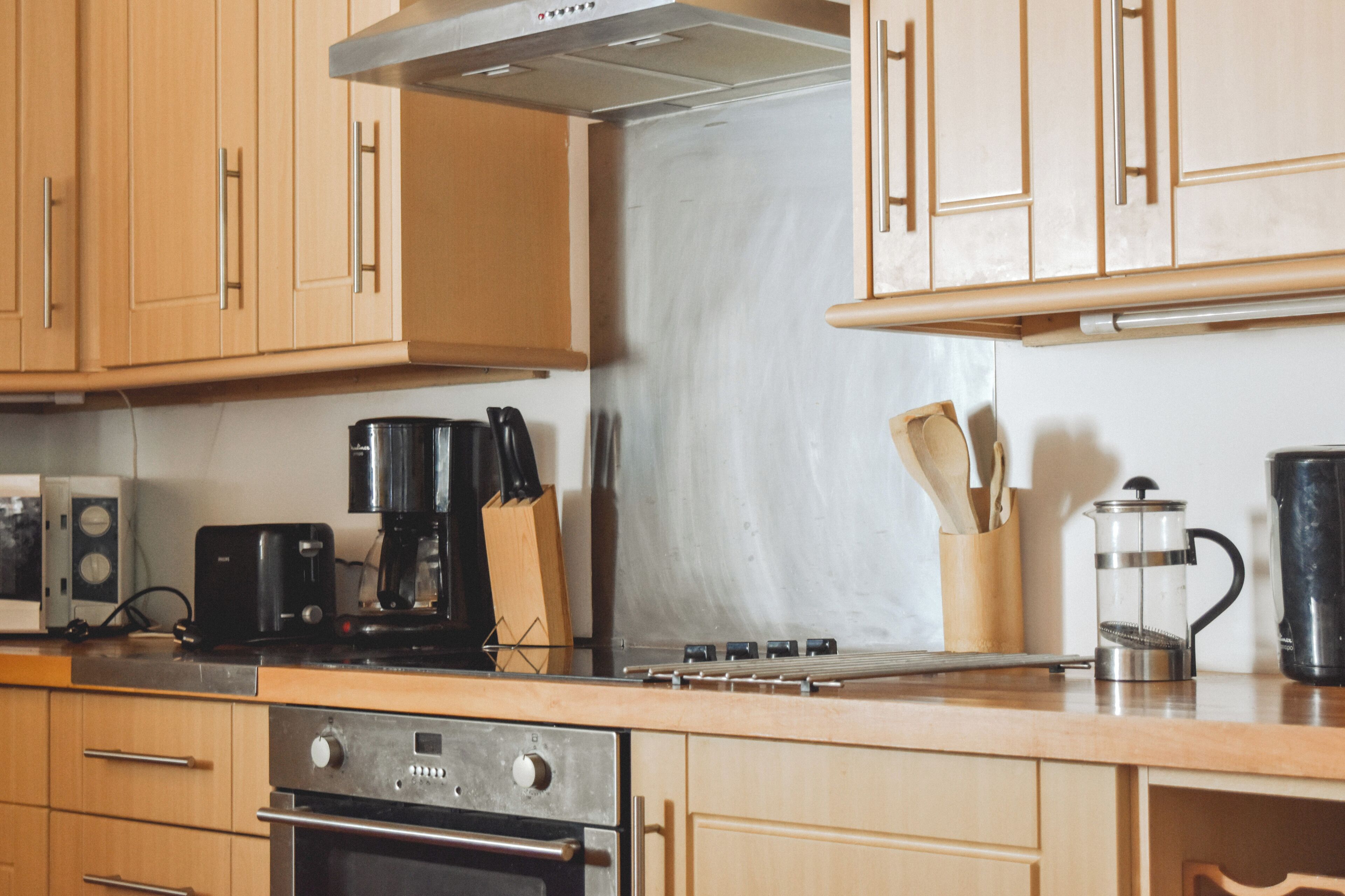 A kitchen with wooden cabinets, a stove, a coffee maker, and a kettle.