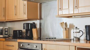A kitchen with wooden cabinets, a stove, a coffee maker, and a kettle.
