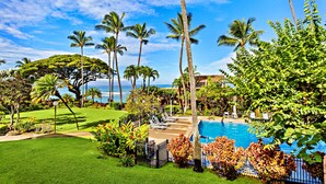 A pool area with lounge chairs, palm trees, and a view of the ocean. - Tropical vibes, sleek style, a peek at the Ocean (Lahaina)