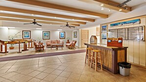 A spacious lobby with wooden ceiling beams, a reception desk, and a seating area with chairs and a sofa. - Tropical vibes, sleek style, a peek at the Ocean (Lahaina)