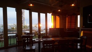 An indoor dining area with large windows, tables, and chairs. - Hotel Centre Point (Dharamshala)