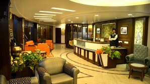 A hotel lobby with a reception desk, seating area, and decorative plants. - Hotel Centre Point (Dharamshala)