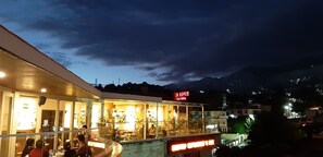 A restaurant with outdoor seating, a mountain backdrop, and a sign indicating it is a restaurant. - Hotel Centre Point (Dharamshala)