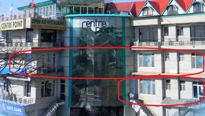A multi-story building with a glass facade, a sign for 'Centre Point' with amenities like a beer bar and conference hall, and a visible staircase leading to an upper level. - Hotel Centre Point (Dharamshala)