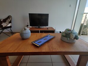 A wooden table with a remote, a decorative vase, and a book. - Charming 1-bed Apartment in Protaras, Cyprus (Paralimni)