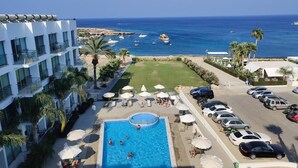 A hotel with a swimming pool, outdoor seating, and a view of the sea. - Charming 1-bed Apartment in Protaras, Cyprus (Paralimni)