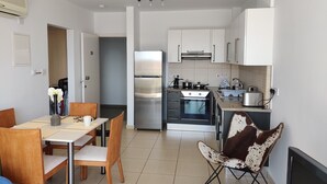 A modern kitchen with stainless steel appliances, a dining area with wooden furniture, and a unique cowhide chair. - Charming 1-bed Apartment in Protaras, Cyprus (Paralimni)