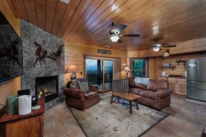 A cozy cabin interior with a stone fireplace, leather sofas, a dining area, and a kitchen. - Write your next chapter at Story Lodge! (Whittier)