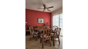 A dining area with a round table and six wooden chairs with cushioned seats.