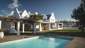 A pool with a clear blue water surface, surrounded by a paved area and white columns.