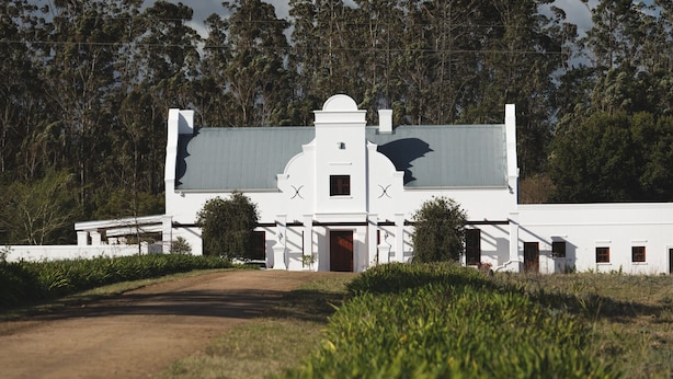 A white building with a central door and a small window on the upper floor.