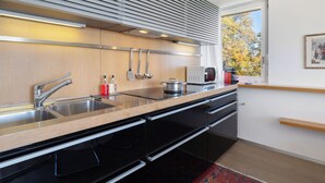 Uma cozinha moderna com uma pia de aço inoxidável, armários de madeira e um forno embutido.
