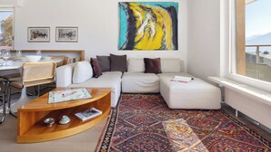 Uma sala de estar moderna com um sofá, uma mesa de centro e uma grande pintura abstrata.