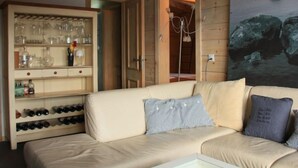 A cozy room with a beige sofa, a wine rack, and a painting of rocks. - Muscardin 5/6 by Interhome (Villars)