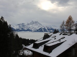A mountain landscape with snow-covered peaks and a view of a building with a sloped roof. - Muscardin 5/6 by Interhome (Villars)