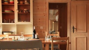 A wooden dining table with chairs, a candle, and a bottle of wine. - Muscardin 5/6 by Interhome (Villars)