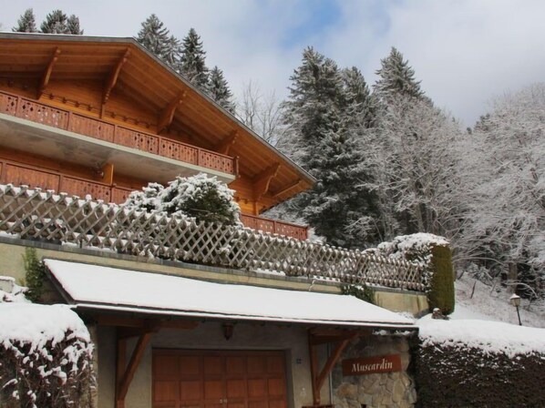 A wooden chalet with a stone entrance, surrounded by snow-covered trees. - Muscardin 5/6 by Interhome (Villars)
