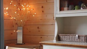A wooden interior with a white cabinet, a wicker basket, and a vase with lights. - Muscardin 5/6 by Interhome (Villars)
