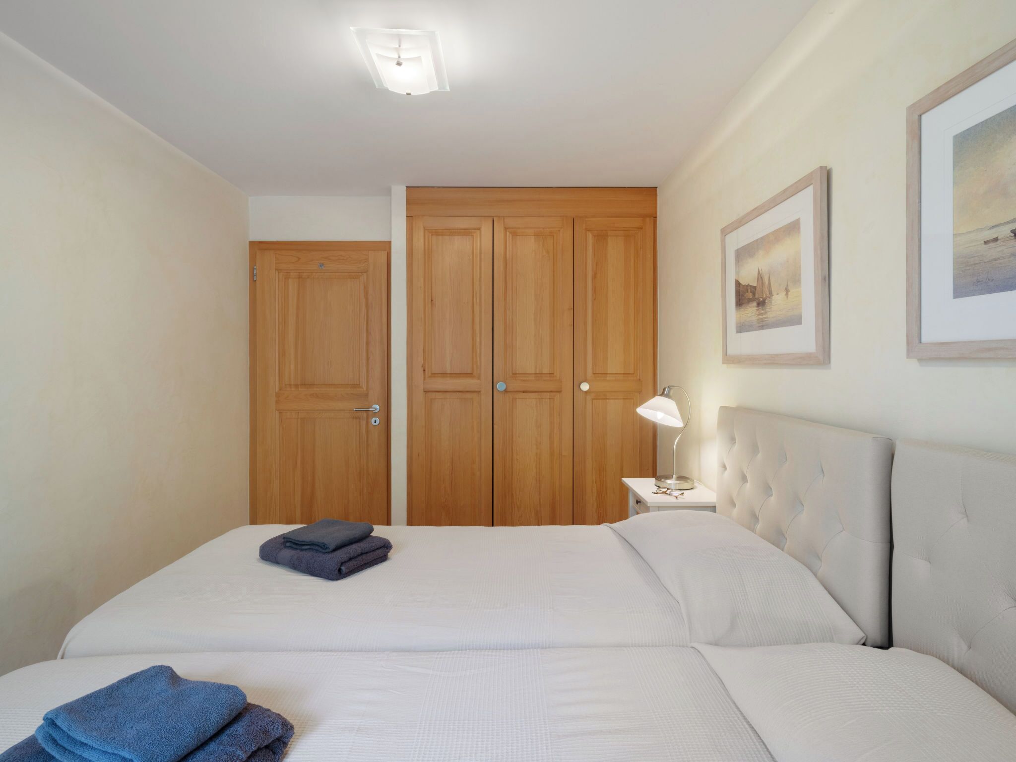 A bedroom with a bed, a nightstand, a lamp, and two doors.